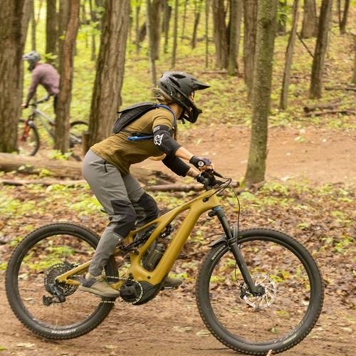 A woman mountain biking on a downhill trail on a yellow bike