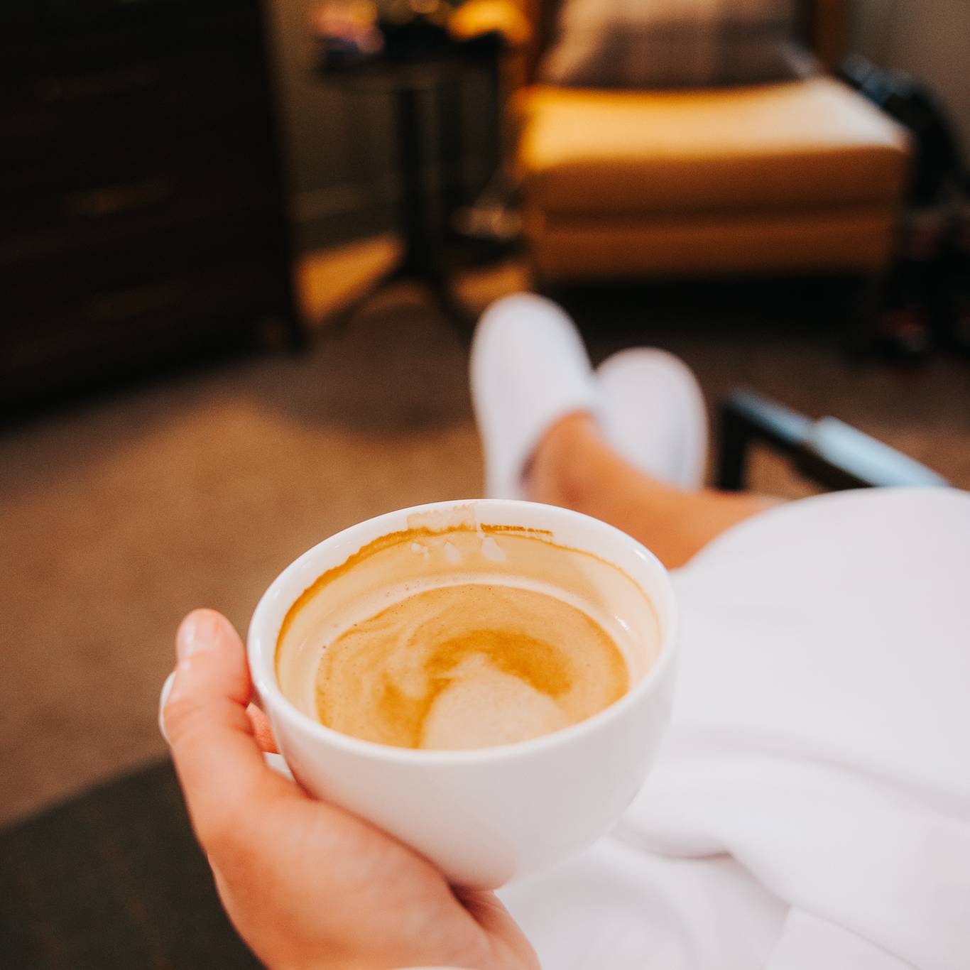 A person holding an espresso in a Main Lodge room at The Highlands