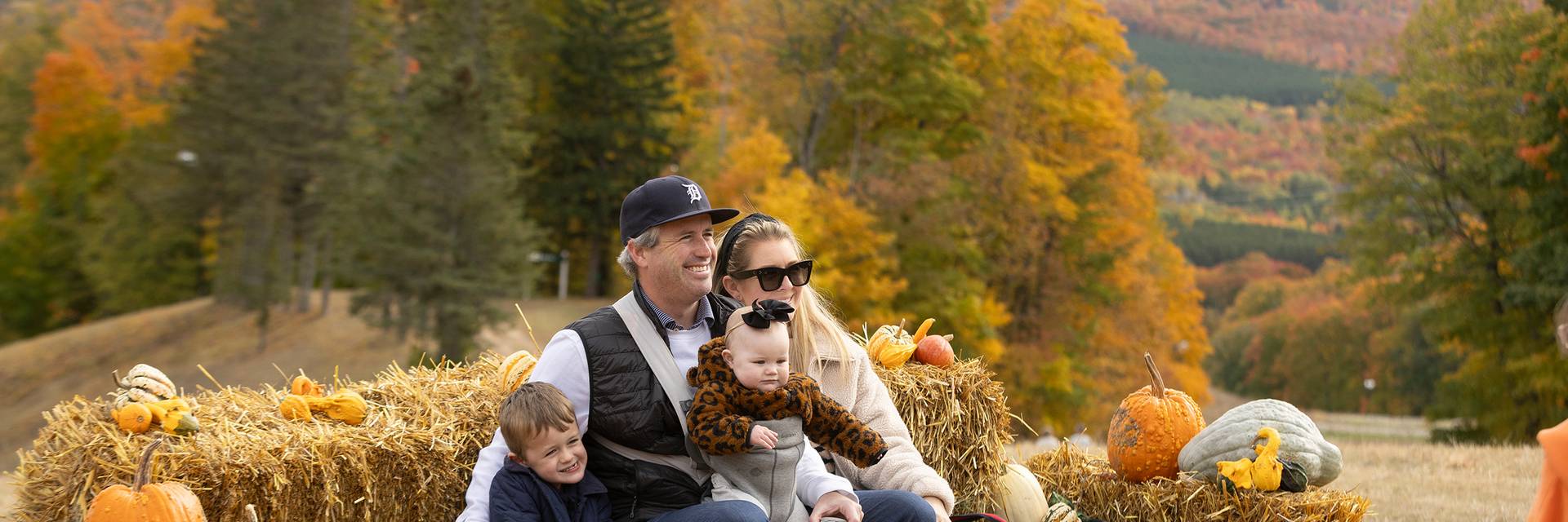 A family posing on a hay bale at The Highlands Harvest Fest