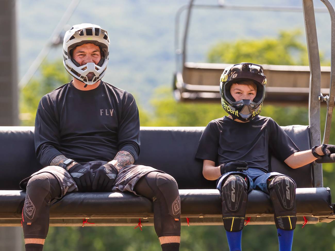 A dad and child in mountain bike gear riding the scenic chairlift