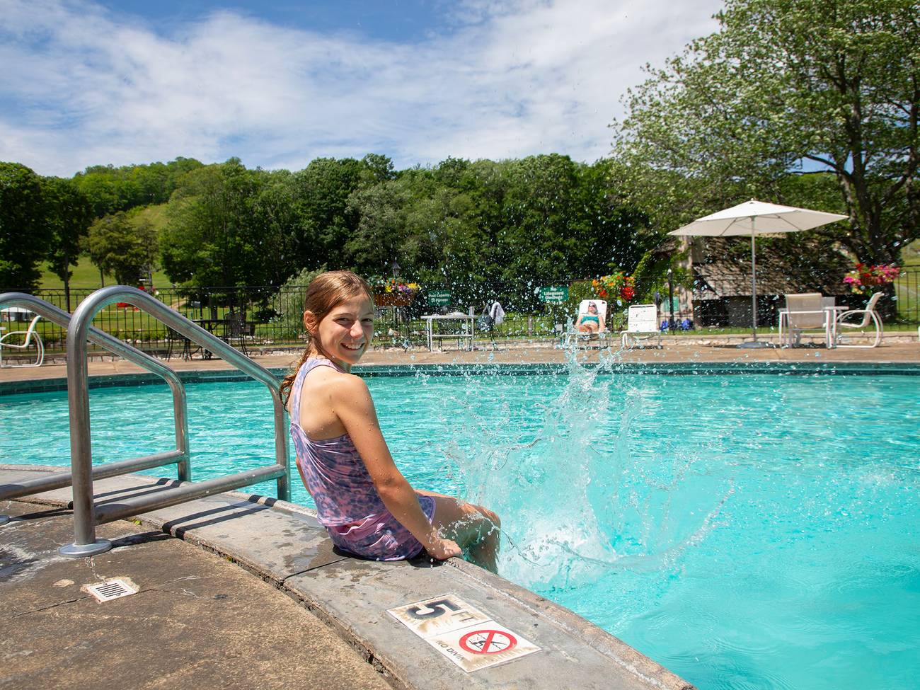A child posing on the edge of the outdoor pool