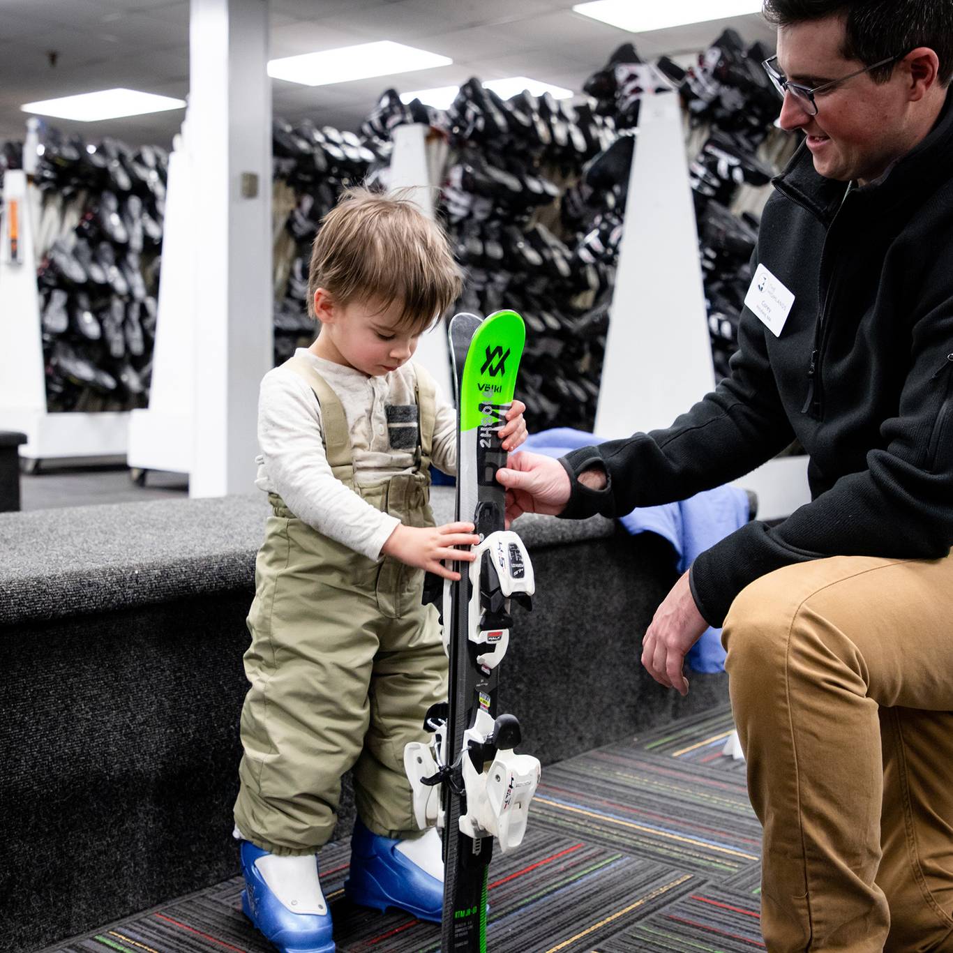 A child holding skis getting fitted for rental equipment at The Highlands